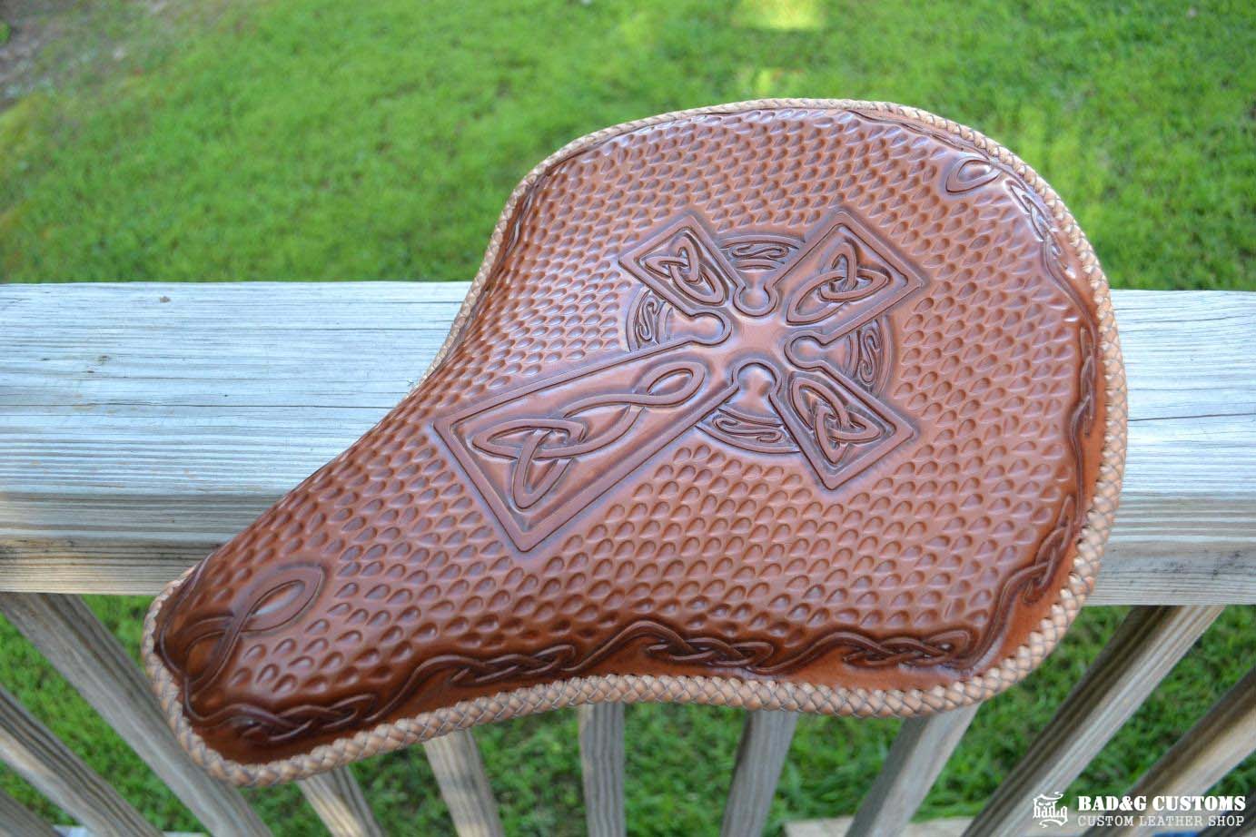 "CROSS" design hand tooled and braided on a chopper solo seat. Brown Veg tan leather with kangaroo lace.