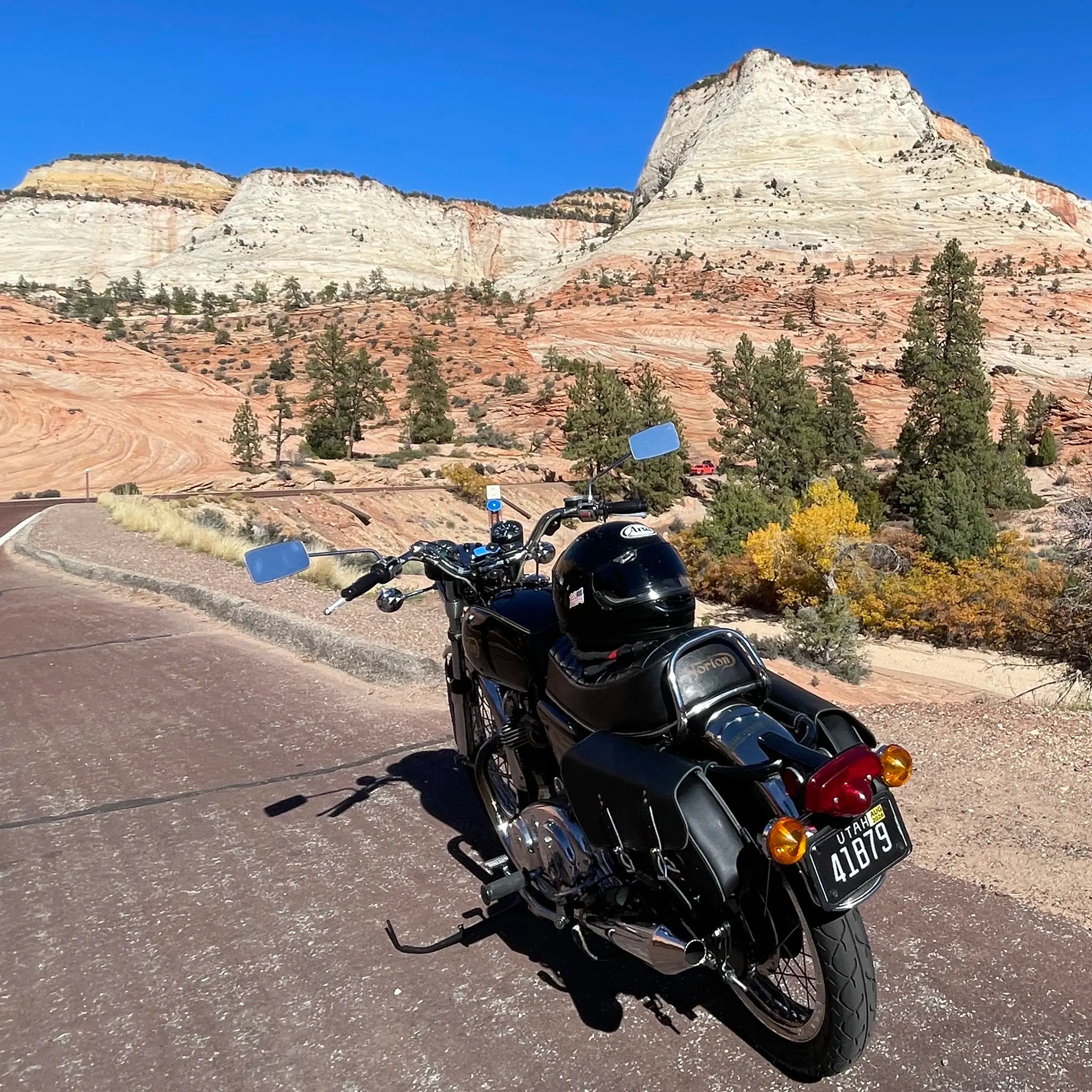 Motorcycle on a road with desert landscape and cliffs in the background