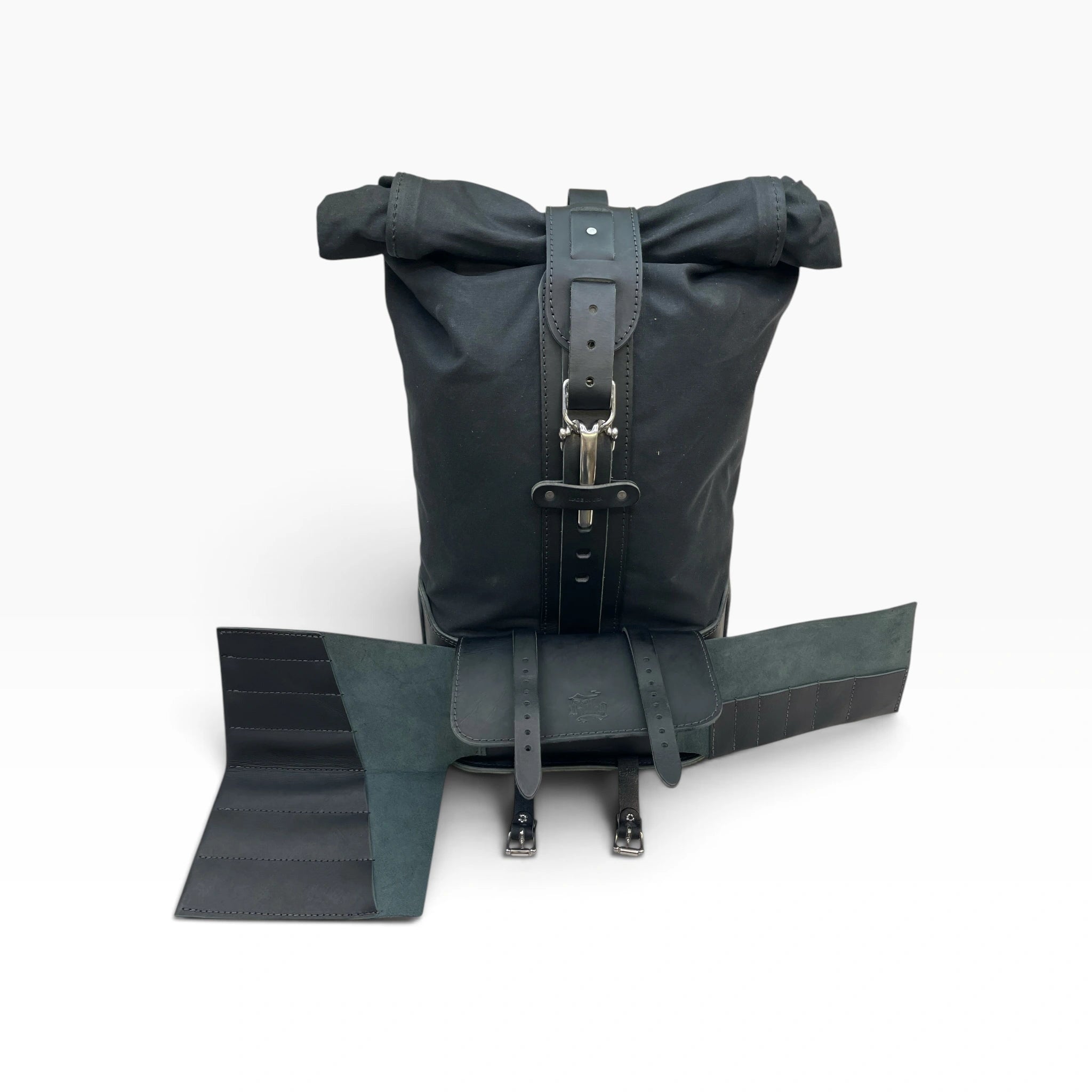 A black roll-top bicycle bag with attached rear rack straps and mounting hardware, photographed on a clean white background.